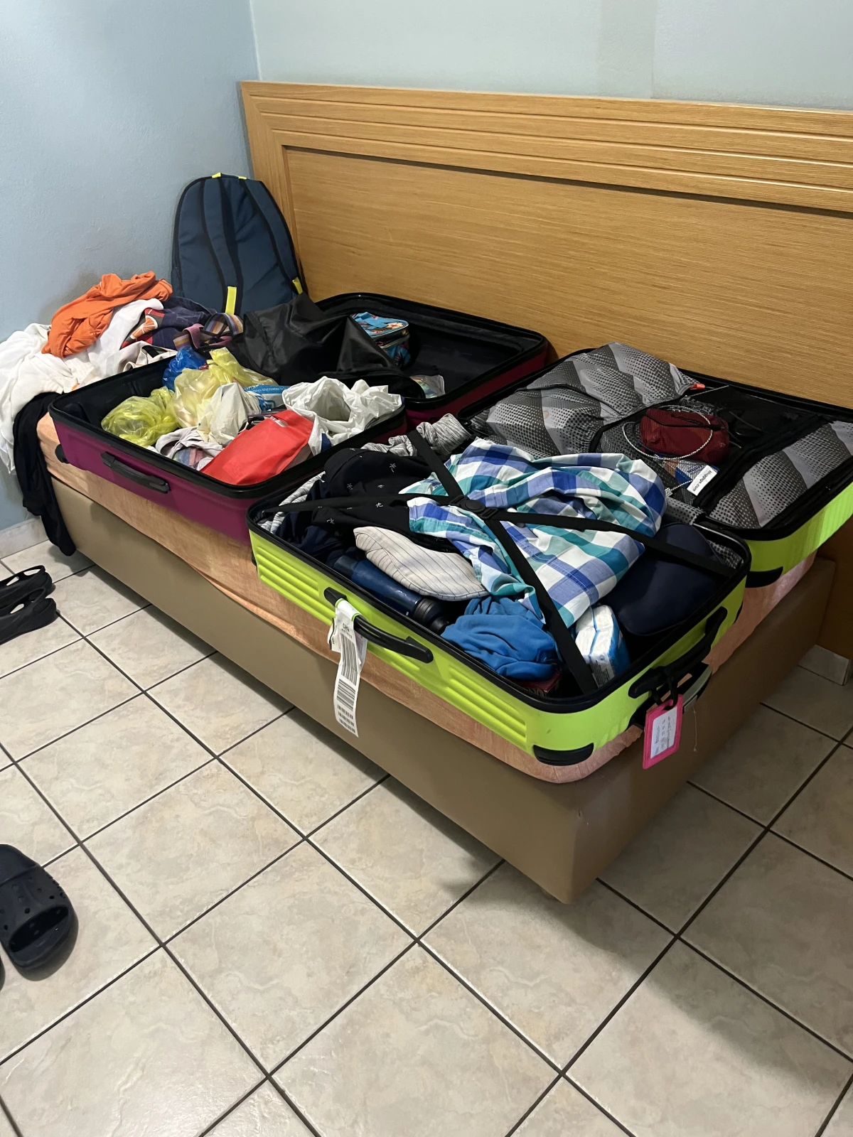 Avoimesti auki oleva matkalaukku täynnä vaatteita hotellihuoneessa.